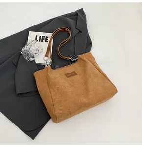 Detalle de bolso tote de pana marrón con etiqueta de cuero y cadena de metal
