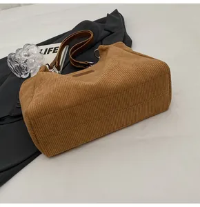 Detalle del bolso tote de pana marrón con textura de rayas y correa de cuero