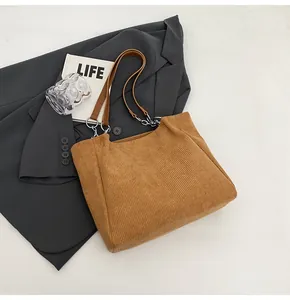 Detalle del bolso tote de pana marrón con correas de hombro de cuero y cadena metálica