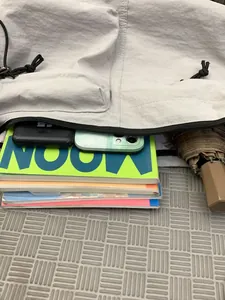 Light gray nylon crossbody bag showing spacious interior with books and daily essentials