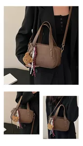 Detail of lychee textured leather mini boston bag with teddy charm and silk scarf