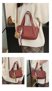 Detail of lychee pattern leather bag with plush bear charm and striped silk scarf