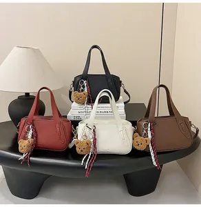 Detail of four retro Boston bags in various colors featuring lychee texture and bear charms