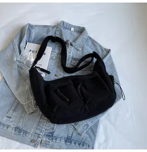 Detailaufnahme einer schwarzen Cord-Umhängetasche mit zwei Taschen und verstellbarem Gurt