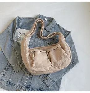 Nahaufnahme der beigen Cord-Tasche mit Vordertaschen auf blauem Jeansstoff