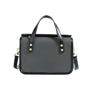 Petit sac carré en toile grise avec bordures en cuir noir et finitions métalliques dorées