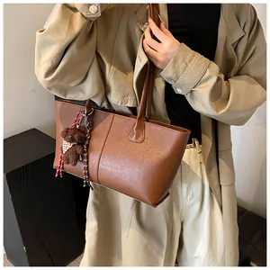 Bruine leren shopper met een kleine beer hanger gedragen bij een kaki trenchcoat outfit