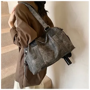 Détail du grand sac cabas vintage taupe porté par un mannequin dans une lumière douce