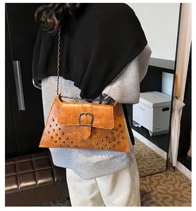 Nahaufnahme braune Vintage-Umhängetasche mit Nieten und Kette am Model getragen