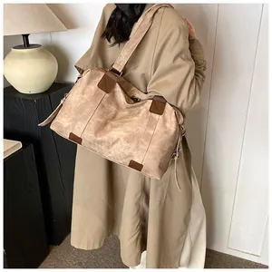 Sac fourre-tout kaki spacieux avec détails en cuir marron porté à l'épaule sur trench