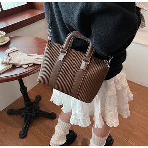 Vue détaillée de la texture plissée verticale et ferrures sur ce sac marron foncé