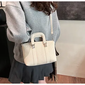 Détail du sac à main crème rayé avec bandoulière élégante porté par un mannequin