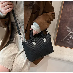 Détail d'un sac à main rayé noir en cuir avec boucle en métal argenté et bandoulière