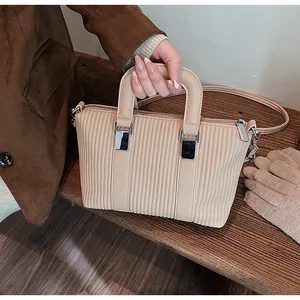 Détail d'un sac à main beige plissé avec texture verticale et boucles en métal argenté