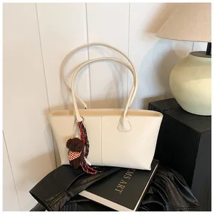 Detail van de crème tote bag met decoratieve pluche beer en gevlochten touw op leer