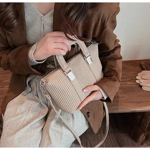 Gros plan du sac beige à texture plissée verticale et détails métalliques argentés polis