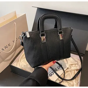 Vue détaillée d'un sac à main en cuir noir texturé avec rayures et boucles argentées