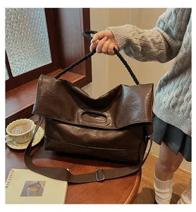 Détail d'un sac cabas vintage marron avec poignée tressée posé sur une table en bois