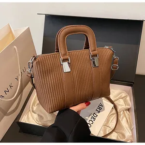 Détail du sac à main marron rayé avec boucles métalliques dans une boîte cadeau