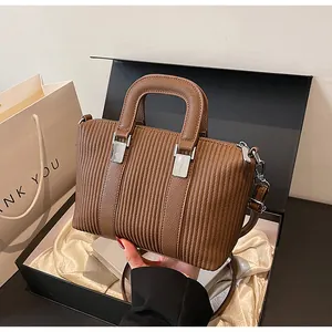 Vue détaillée d'un sac à main plissé marron foncé dans une boîte cadeau avec doublure