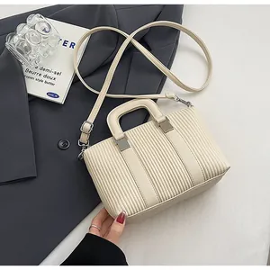 Détail du sac à main crème en cuir avec texture plissée verticale et boucles métalliques