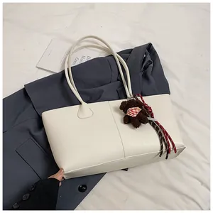 Detail van crème tote bag met lederen textuur en een schattige bruine pluche beer