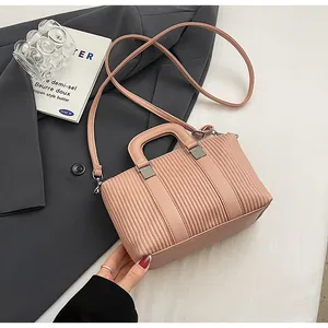 Détail du sac bandoulière rose poudré avec texture plissée et finitions argentées