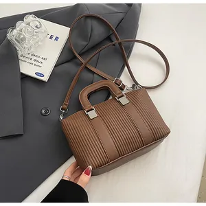 Gros plan détaillé sur la texture plissée marron et les boucles de ce sac à bandoulière