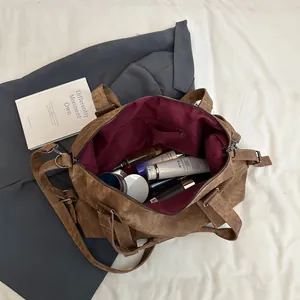 Grand sac cabas marron en cuir souple avec bandoulière dans une scène de voyage