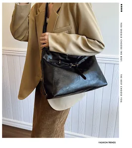 Detalle del bolso tote de cuero negro brillante con hebilla dorada y correa elegante