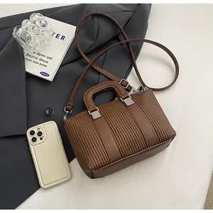 Détail d'un sac à main marron à texture plissée avec boucle en métal et bandoulière