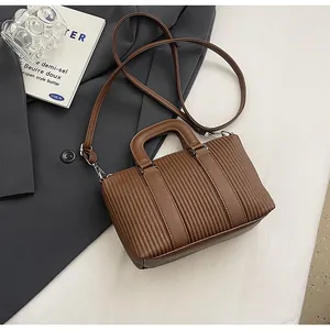 Détail d'un sac à main marron à texture plissée avec poignée et boucle argentée