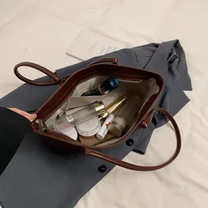 Bruine kunstleren shopper op grijze blazer met grote inhoud voor uw cosmetica