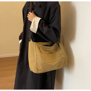 Detail of khaki canvas messenger bag featuring contrast white stitching and metal buckle