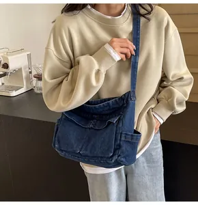 Detail of dark blue denim crossbody bag with multiple utility pockets in a lifestyle setting