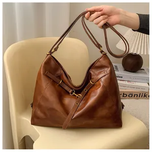 Primer plano de un bolso hobo grande de cuero marrón oscuro con hebillas metálicas vintage
