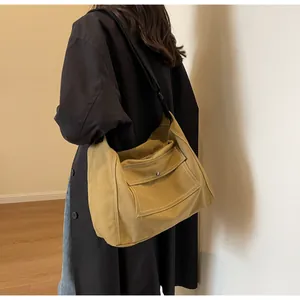 Detail of canvas messenger bag in mustard yellow with contrast stitching and metal snap