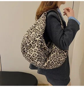 Detail of a large leopard print tote bag worn as an underarm shoulder bag on a model
