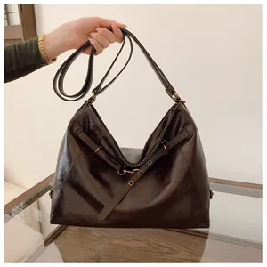 Primer plano del bolso hobo marrón brillante con hebilla dorada y acabado de cuero