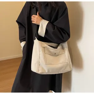 Detail of off-white canvas messenger bag with black nylon strap and front cargo pocket