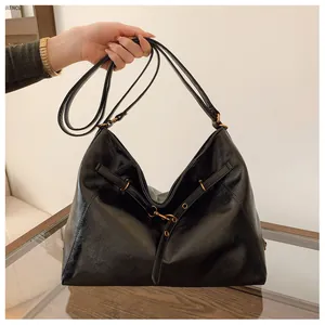 Detalle del bolso tote vintage de cuero aceitado negro con hebilla de bronce retro