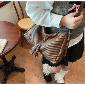 Detail of brown pleated tote bag featuring tassel charm and silver chain accents