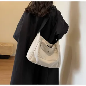 Detail of a large capacity off-white canvas tote bag worn by a model in a casual setting
