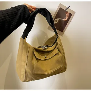 Detail of mustard yellow canvas messenger bag with wide black strap and metal buckle
