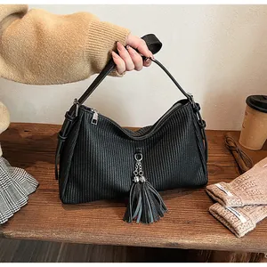 Close-up of black pleated faux leather shoulder bag with silver chain and fringe detail