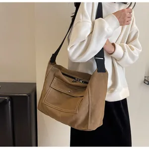 Close-up of brown canvas messenger bag showing white topstitching and adjustable strap