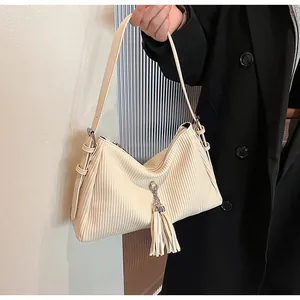 Close-up of cream corduroy shoulder bag with fringe tassel detail and textured finish
