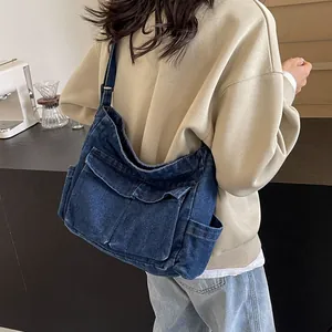 Deep blue washed denim crossbody bag featuring large front pockets and adjustable strap