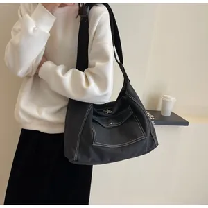Detail of black canvas messenger bag with white contrast stitching and spacious pockets