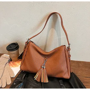 Detail of brown hobo tote with vertical pleated texture and leather tassel pendant